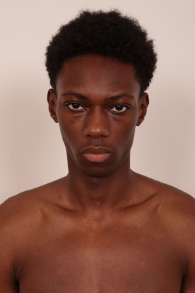 Male model with a natural afro hairstyle and striking gaze, showcasing a raw and authentic portrait
