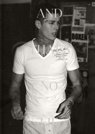 Norman Theuerkorn male model, close-up tattooed chest, white V-neck tee, sharp daylight contrast