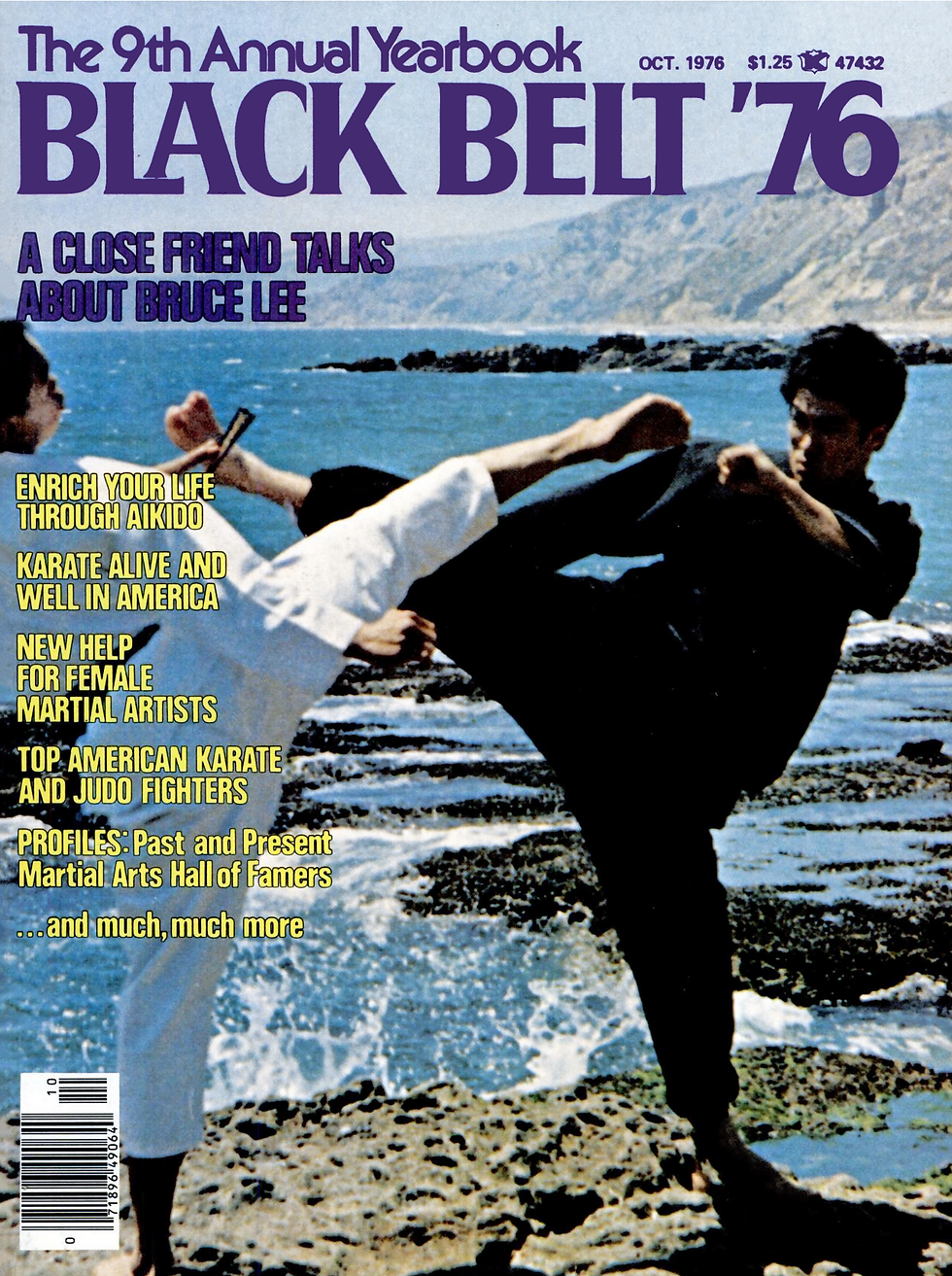 Two martial artists in black and white outfits spar on rocky shore. "Black Belt '76" text on top; ocean and hills in the background.