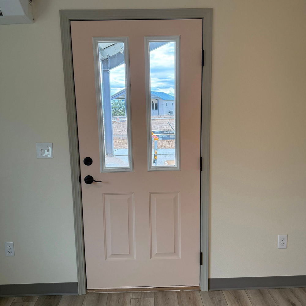 Light-colored interior door with glass panels overlooking a landscape