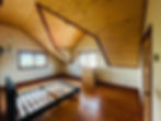 Empty room with sloped wood ceiling, bed frame, and dresser