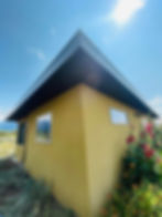 Yellow house exterior with red roses under a bright sunny sky