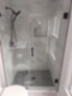 Modern glass walk-in shower with black fixtures and tile floor