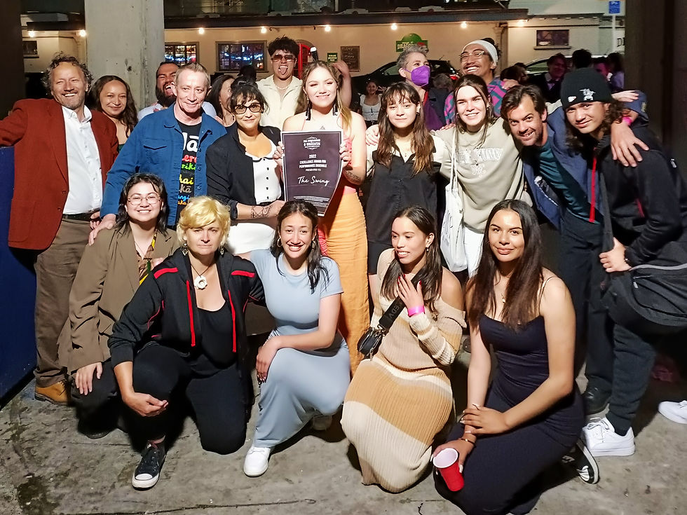 A large group of people gather together for a photo, some crouched on the groun and others celebrating behind them
