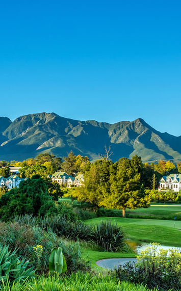 A scenic view of a golf course with mountains in the background