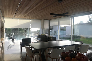Dining area with a timber ceiling and large glass doors fitted with roller blinds