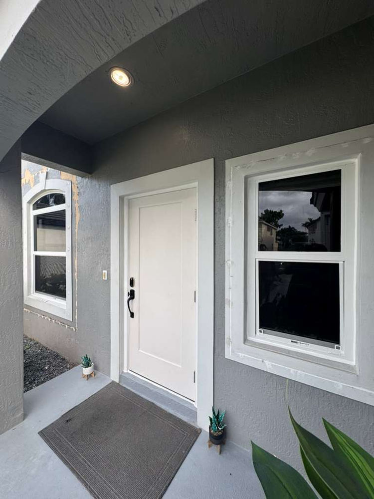 New entry door and impact windows on a gray home