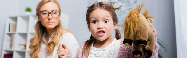 Femme affichant une expression de mépris en regardant l'enfant de son partenaire, illustrant la tension dans une dynamique de famille recomposée