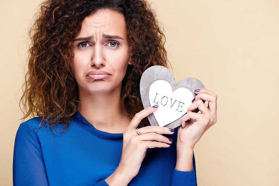 Une femme au visage triste, tenant un cœur avec l'inscription "I love you", symbolisant la mélancolie liée au célibat
