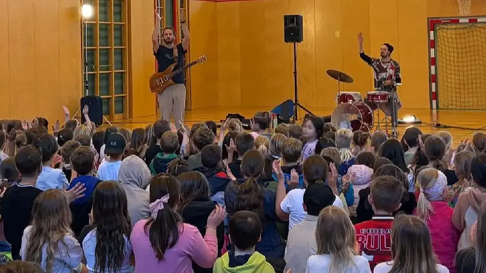 Mitmachkonzert Austro Rock 4 Kids in Fohnsdorf mit Musikerinnen und Musikern auf der Bühne und begeisterten Kindern im Turnsaal