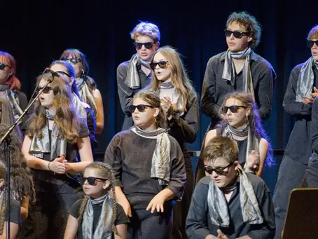 Schülerinnen und Schüler des Vokalensembles des BG/BRG Knittelfeld mit Sonnenbrillen und silbernen Schals beim Konzert „A Million Dreams“ im Kulturhaus