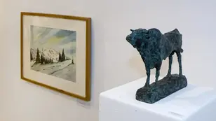 Galerie mit gerahmtem Winterlandschaftsbild und dunkler Rind-Skulptur auf weißem Podest.