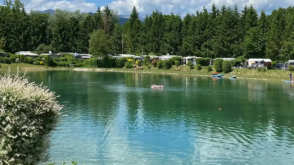 Hopf-Teich beim Campingplatz Murinsel in Großlobming mit klarem Wasser, umliegenden Stellplätzen und Naturkulisse als Veranstaltungsort für das Anpaddeln auf der Mur.
