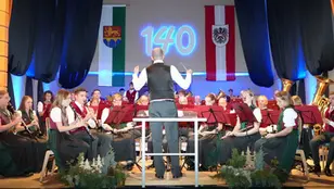 Kapellmeister Thomas Pöllinger dirigiert den Musikverein St. Oswald-Möderbrugg auf der Bühne beim Neujahrskonzert im Gemeindezentrum Pölstal.