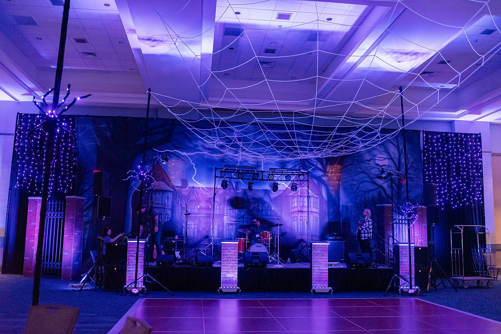 Haunted mansion stage design for corporate Halloween gala with giant overhead spiderweb