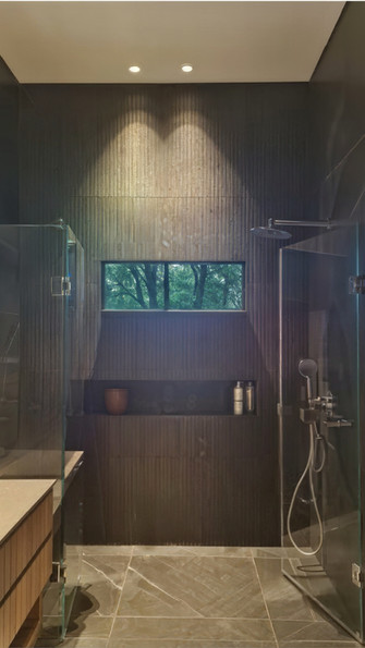 חדר רחצה מחופה אבן אפורה וטיבעית, עם חלון שפונה לבחוץ למראה עצים