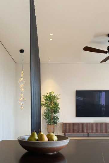 מבט מכייון המטבח לכיוון הסלון, עם מעקה כבלים וקערת אגסים ברקע