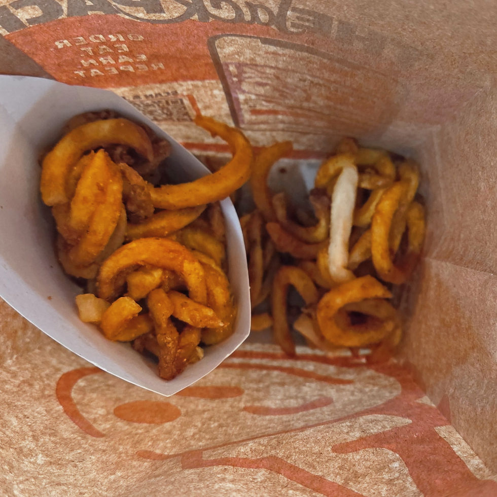 Jack in the Box curly fries in a carton, all in a brown bag