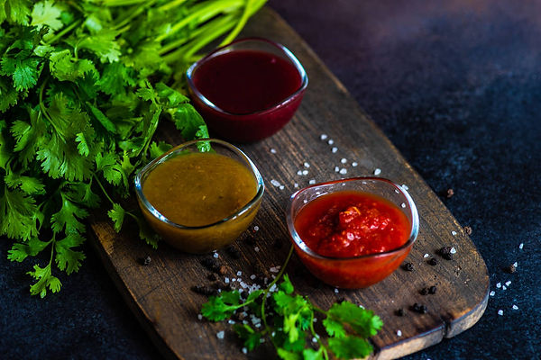 Three varieties of August Georgian fruit sauce served 
in bowls with fresh herbs, traditional Caucasian condiments