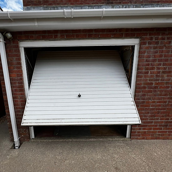 Open garage door revealing the exterior, with an additional door also ajar, inviting access to the outside