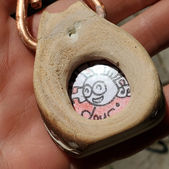 Close up detail shot of a hand crafted wooden amulet made of eucalyptus wood. Featuring a cute IW Comics cartoon character inside