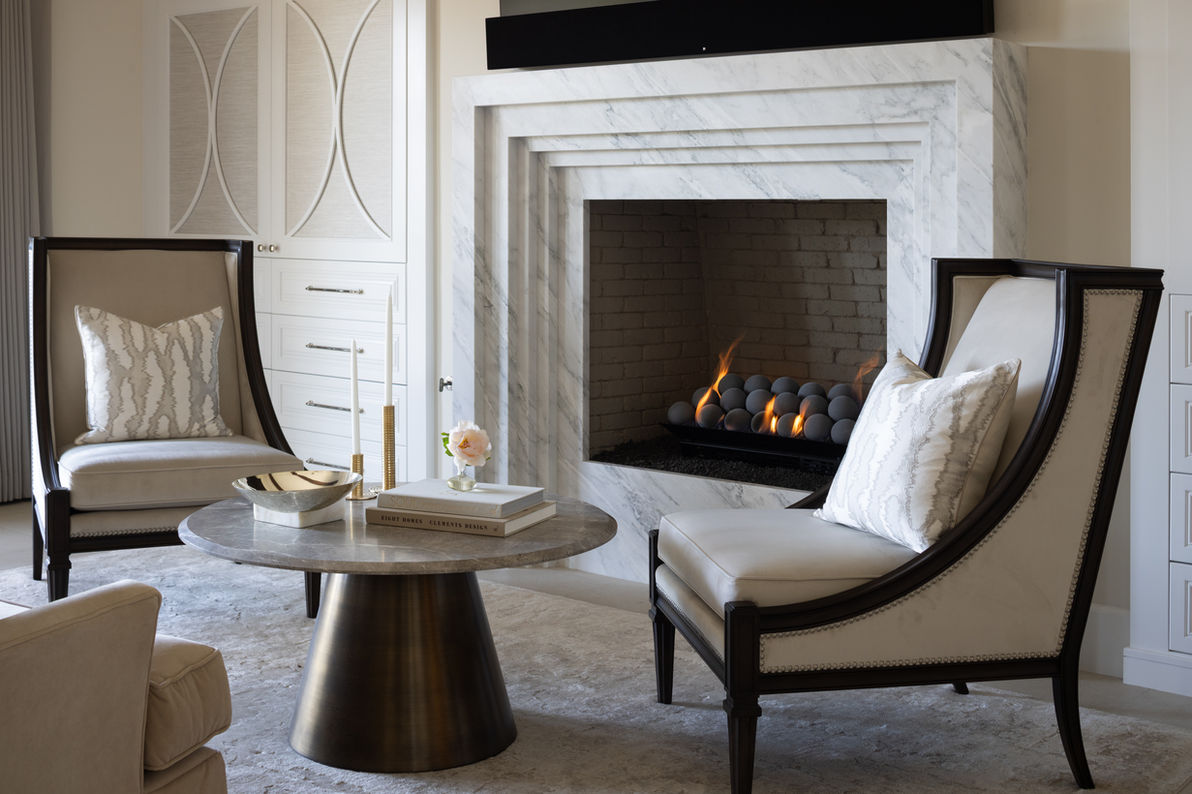 Contemporary seating area featuring white marble fireplace surround, leather accent chairs, round pedestal table, and clean-lined design in contemporary Rancho Santa Fe home designed for entertaining by interior designer Liz Tapper