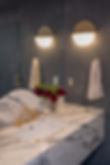 Modern powder room with grey limewashed walls, marble vanity, unlacquered brass fixtures, and modern sconce lighting by Los Angeles interior designer Liz Tapper