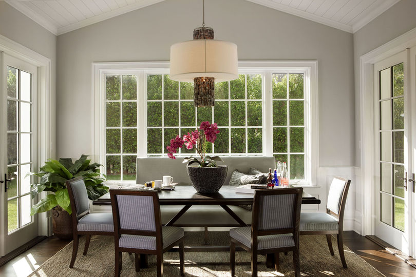 Transitional breakfast nook with vaulted ceiling, wall of windows, dark wood table, and natural light in Brentwood home by Liz Tapper Interiors