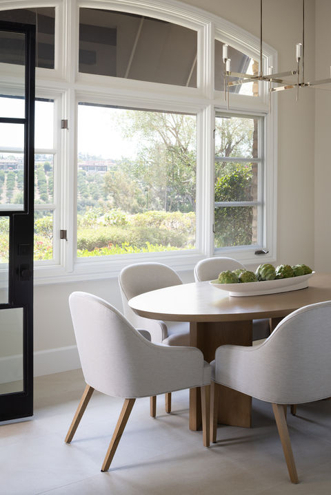 Beautifully modern breakfast nook in Rancho Santa Fe. White oak oval dining table with grey upholstered dining chairs and modern light fixture.