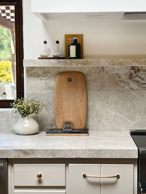 Transitional kitchen detail with Taj Mahal quartzite counters, stone shelf, and natural wood cutting board in Rancho Santa Fe home by Liz Tapper Interiors