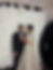 Bride and groom posing in front of a white floral backdrop at a wedding with the LightBox photo booth visible.