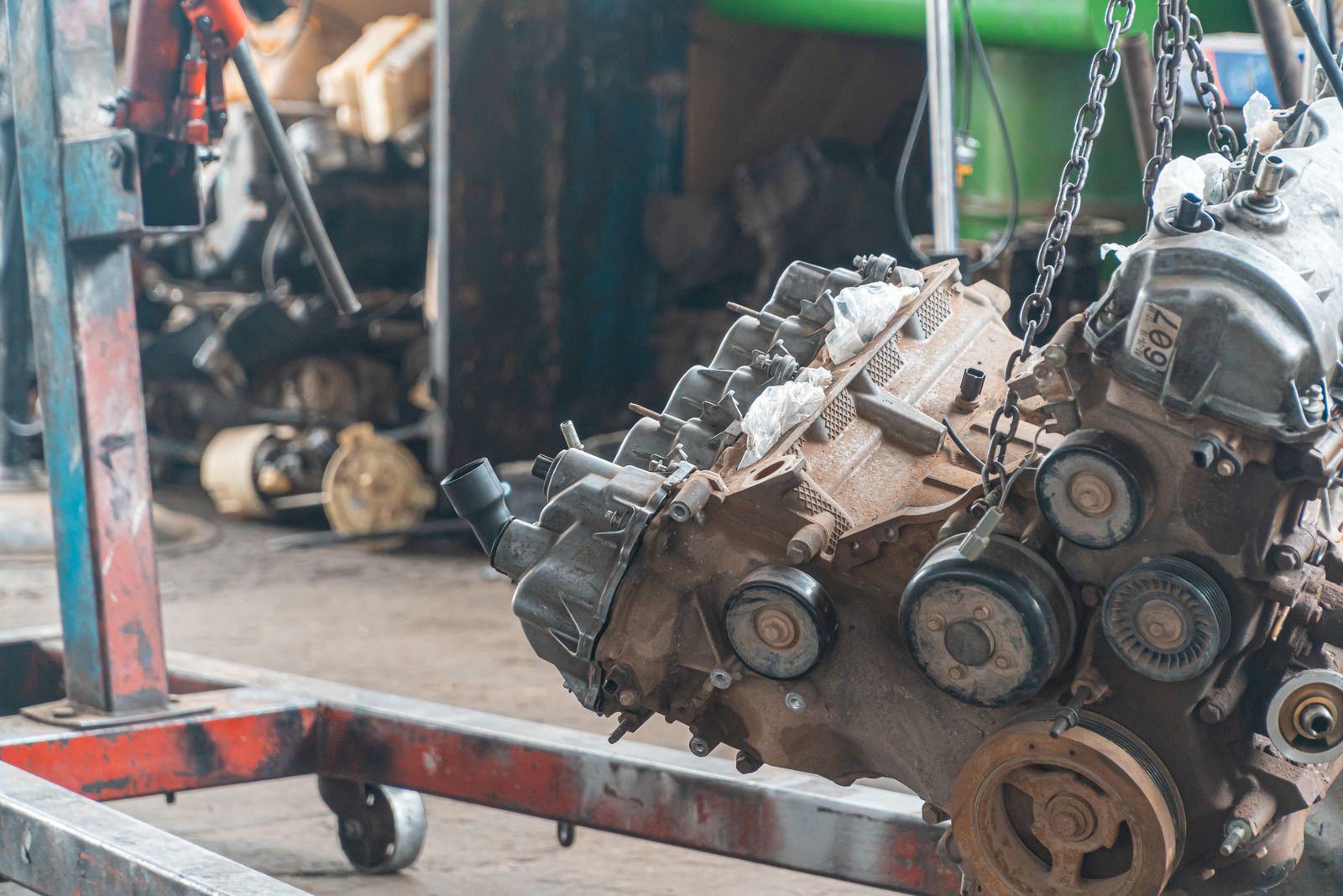 Actual automobile engine suspended by a lifting chain during removal, stock photo