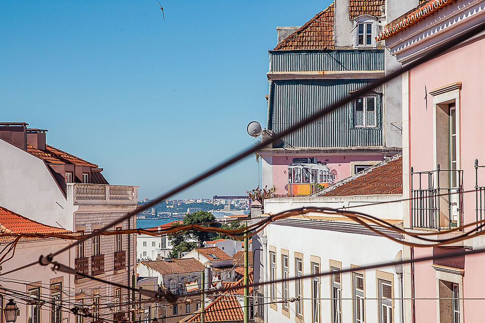 Vacker utsikt över Lissabon me rosa hus, spårvagnar, floden och havet.