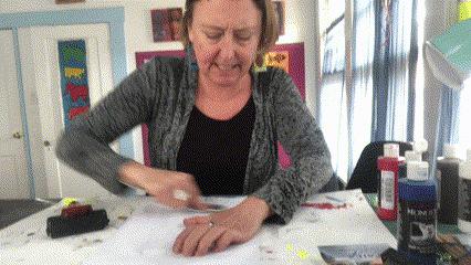 This image shows an artist pressing a print of an animal ontoa piece of paper.