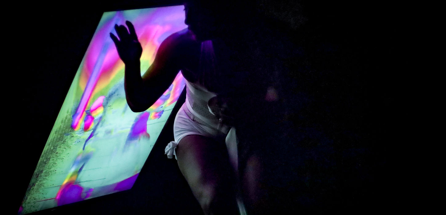 Texto alternativo: Performance transmedia Otrx de Lucio Bazzalo y Mariana Cinat con artistas en escena, pantallas y dispositivos tecnológicos interactivos.