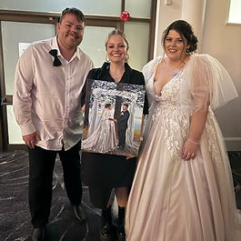 artist standing with couple that are in wedding attire with finished unique individualised painting