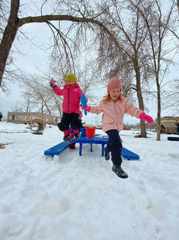 Two children are running and jumping in a park in Wintertime
