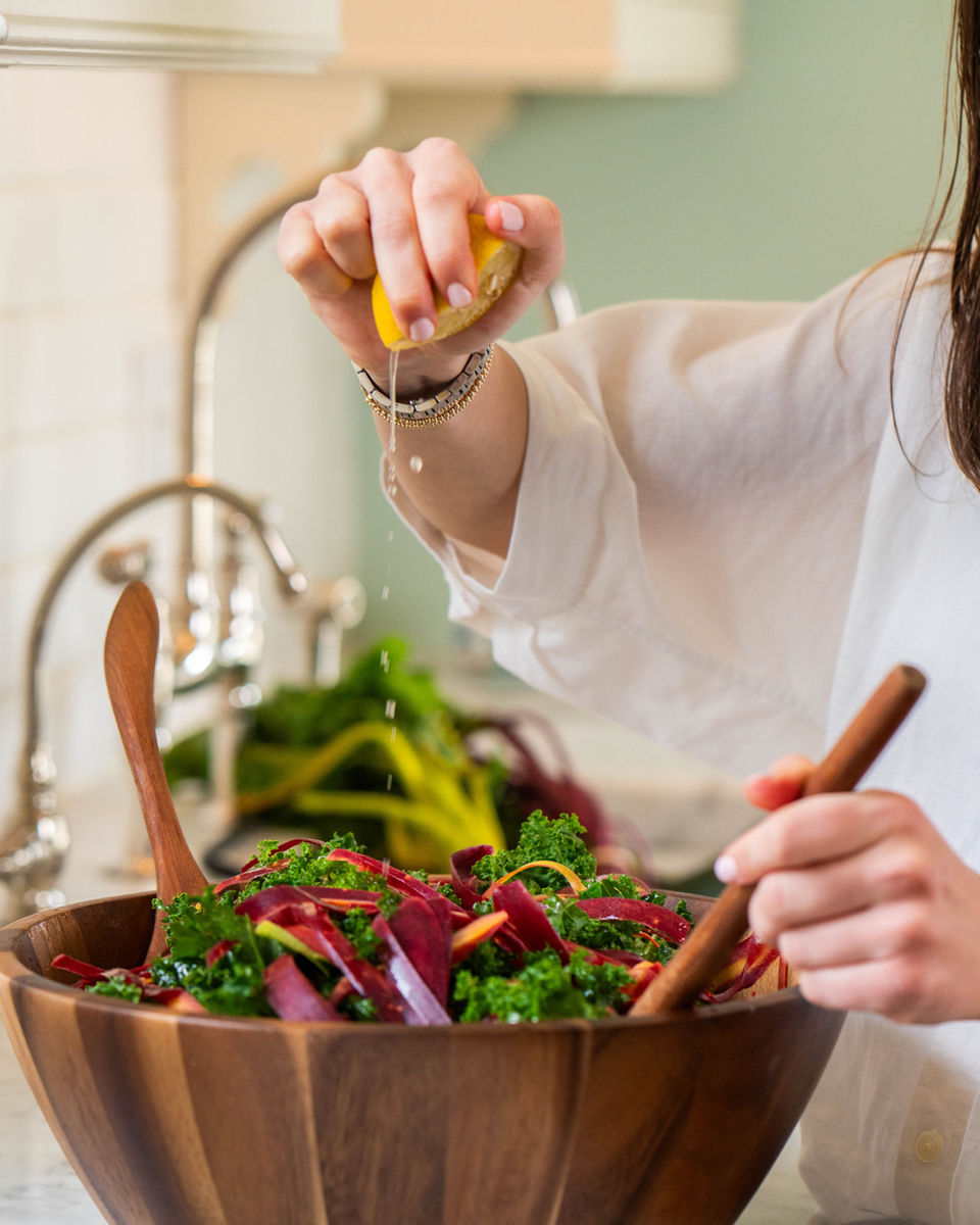 Squeezing lemon over a kale and beet salad