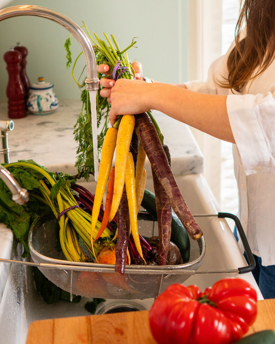 Rinsing rainbow carrots and beets at the kitchen sink