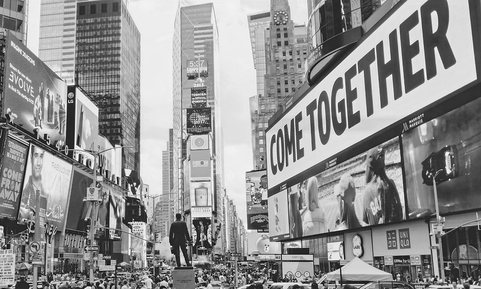 A photo of Times Square in New York with a large poster saying "Come together"