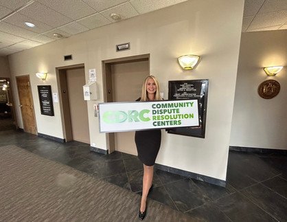 Courtney Chicvak holding a CDRC (Community Dispute Resolution Center) sign at the Office of Court Administration meeting. She stands proudly, showcasing the CDRC sign as a symbol of her involvement and commitment to community mediation efforts. Courtney Chicvak, Courtney Anne Chicvak, Cornell University, Columbia University, Mediation, Negotiation, Conflict Resolution, St. John's Law, Attorney, Coach, United Nations, Chicvak, Mediator, Negotiator, Coach, Community Dispute Resolution Centers