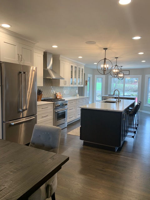 Enlarged kitchen with white cabinets and cherry island