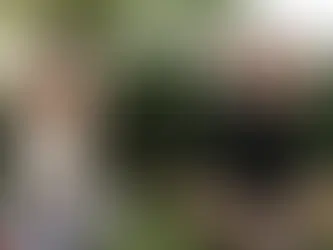 A man and a woman sit cross-legged on grass, arms overhead in a stretch. They appear relaxed and focused.