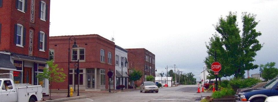 Red brick storefronts along the main street in downtown Wentzville on an overcast morning.