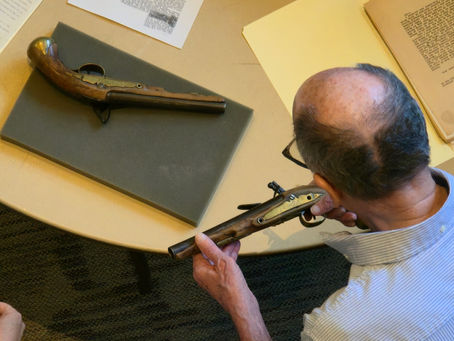 A man examining old pistols 
