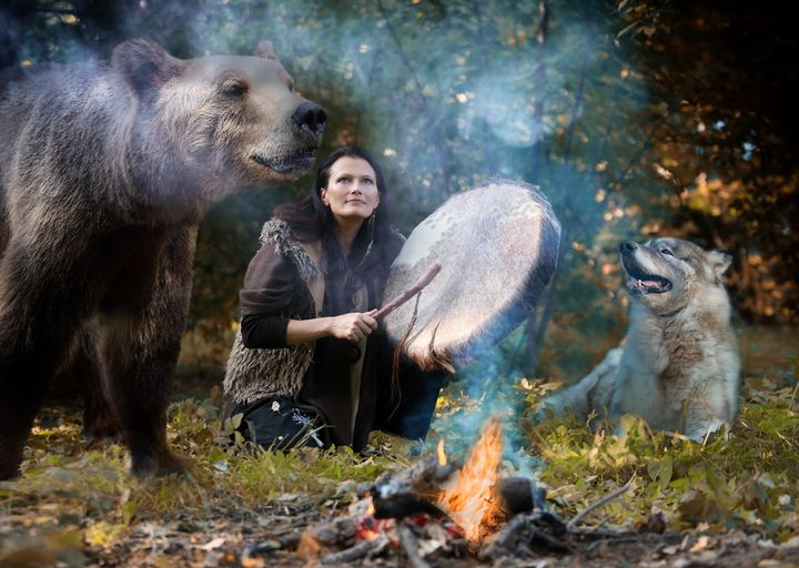 Femme avec un loup et un ours dans la nature autour d'un feu