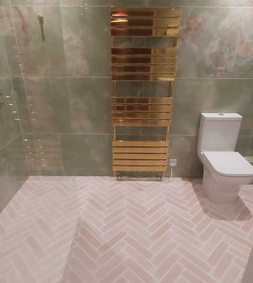 green marble clad bathroom with gold heated towel rail