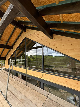 Timber frame roof structure with glazed balcony on a new build