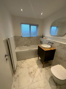 Modern bathroom with marble floor, white bathtub, dark wood vanity