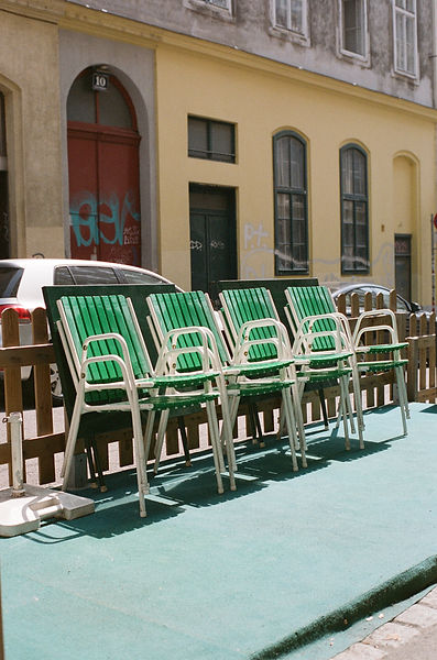 Green chairs stacked up outside a cafe in Vienna
